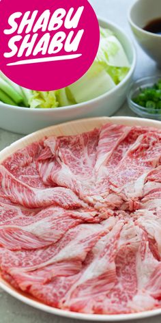 a plate with raw meat on it next to bowls of vegetables