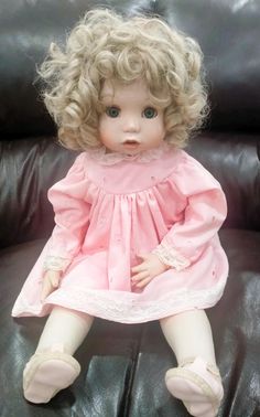 a doll sitting on top of a black leather couch