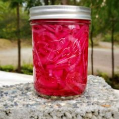 a jar filled with red liquid sitting on top of a rock