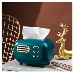 an alarm clock and tissue dispenser sitting on a table next to gold deer figurines