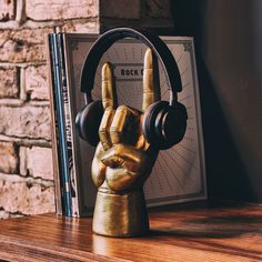 a golden hand with headphones on top of a wooden table next to a book