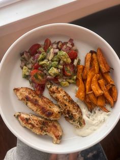 a white plate topped with chicken and veggies next to a side of sweet potato wedges