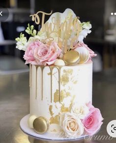 a white and gold cake with flowers on top