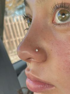 a close up of a person with a nose piercing in their left ear and the other side of her face