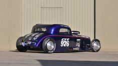 an old fashioned race car parked in front of a garage door with the number seventy on it's side