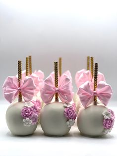 four white and pink candy apples with bows on them are sitting side by side in front of each other