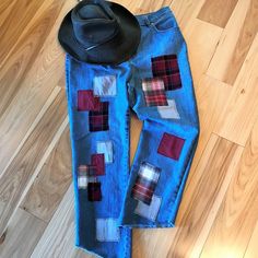 a pair of jeans with patchwork on them and a hat laying on the floor