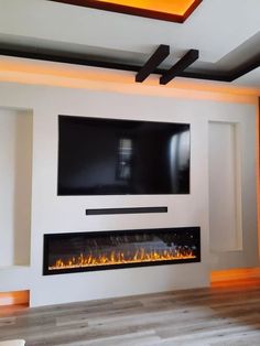 a large television mounted on the wall above a fire place in a room with wood flooring