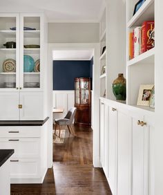 an empty kitchen with white cabinets and wood flooring is pictured in this image from the hallway to the dining room