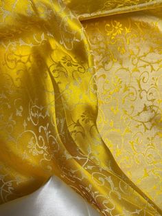 a yellow and white fabric with an intricate design on the top, as well as other material