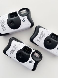 three cameras sitting next to each other on top of a white surface with black and white designs