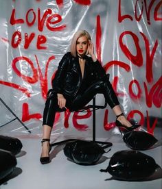 a woman sitting on top of a chair in front of a wall covered with graffiti