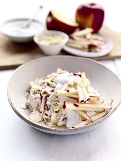 a bowl filled with food sitting on top of a white table next to an apple