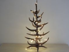 a christmas tree made out of antlers with lights on it's branches is shown in front of a white wall