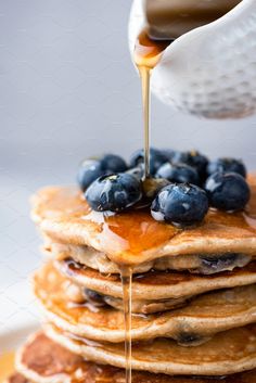 a stack of pancakes with syrup being poured on top