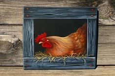 a painting of a chicken in a frame on a wooden table next to wood planks