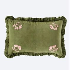 a green pillow with pink flowers and ruffles on the front, against a white background