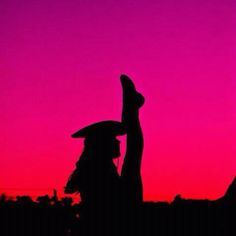 two people are silhouetted against a pink and purple sky at sunset with one holding up the other's hand