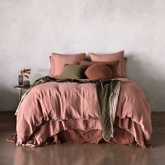 the bed is made with pink linens and green throw pillows on top of it