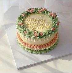 there is a cake decorated with flowers and leaves on the top layer that says happy birthday