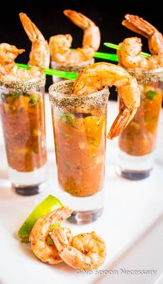 several glasses filled with shrimp and garnish on top of a table