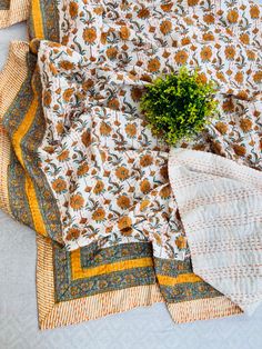 an arrangement of quilts and a potted plant on a bed sheet with white sheets