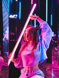 a young woman is posing with a light saber