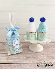 two frosted cupcakes are sitting on a cake plate with a blue bow