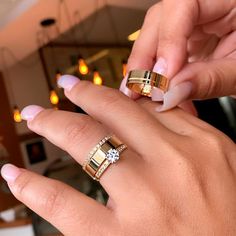 two hands holding onto each other with gold rings on their fingers and one has a diamond in the middle