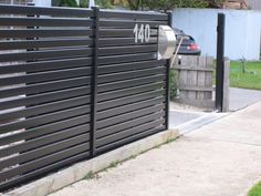 a parking meter on the side of a road next to a fence and grass area