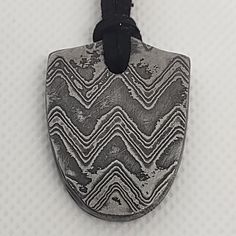 Elevate your style with our exquisite Damascus Shield Pendant, a one-of-a-kind piece meticulously curated by Serene Chaos Forge. This pendant is not just an accessory; it's a statement of strength and artistry. Carefully selected Damascus steel has been expertly shaped into a shield, creating a wearable piece of art that is as unique as it is mesmerizing. ⚒ Craftsmanship: This Damascus Shield Pendant is a testament to our dedication to curation and quality. The Damascus steel, known for its capt Symbols Of Strength, Suede Cord, Damascus Steel, Damascus, Meaningful Gifts, Pendant Necklaces, Unique Pieces, Timeless Design, Jewelry Necklace Pendant