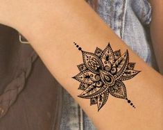 a woman's arm with a black and white tattoo design on the wrist,