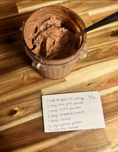 a wooden table topped with a cup of chocolate ice cream