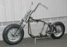 an unusual looking motorcycle parked in front of a white building with metal bars on it