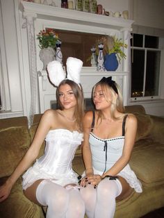 two women in bunny ears are sitting on a couch and one woman is wearing a white corset