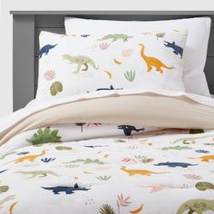 a bed with dinosaurs and plants on it