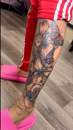 a woman's legs with flowers and butterflies tattooed on her left leg, along with pink shoes