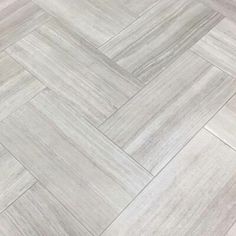 a white tile floor with grey herrings on the bottom and one end in an irregular pattern