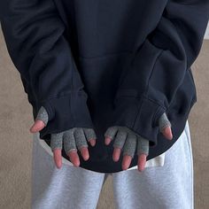 a person with their hands on the back of his hoodie and wearing grey gloves