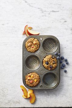 an apple and blueberry muffin in a muffin tin with apples on the side