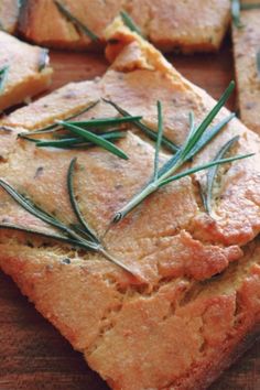 slices of bread with rosemary sprigs on them sitting on a cutting board, ready to be eaten