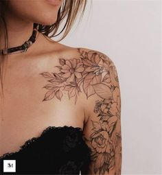 a woman wearing a black dress with flowers on her chest and arm tattooing it's upper half