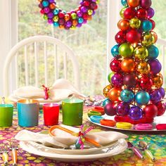 christmas tree decorated with colorful ornaments and decorations on the table in front of a window