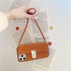 a woman is holding a brown purse over an open book with her finger on the handle