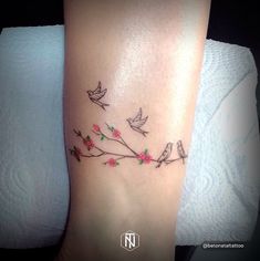 a small tattoo on the leg of a woman with birds flying over flowers and leaves