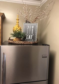 a silver refrigerator freezer sitting in a kitchen next to a wooden cabinet with an eat sign on it