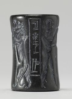 a black vase with an egyptian design on the front and side, depicting two men standing next to each other