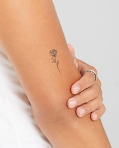 a woman's arm with a rose tattoo on the left side of her arm