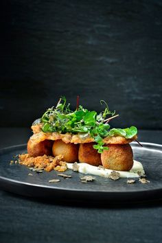 a black plate topped with food and garnish