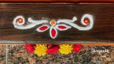 some flowers are sitting in front of a piece of wood that has been painted with white and red paint